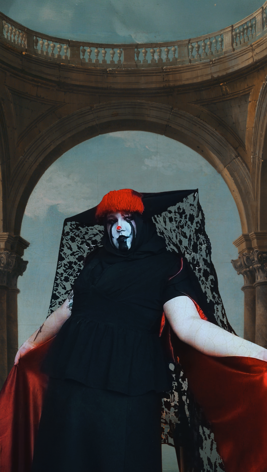 White face paint single red dot on the nose, semi taraz and Italian spiked hat with semi transparent lace going down the back, black skirt, and black blouse that semi looks victorian with buttons